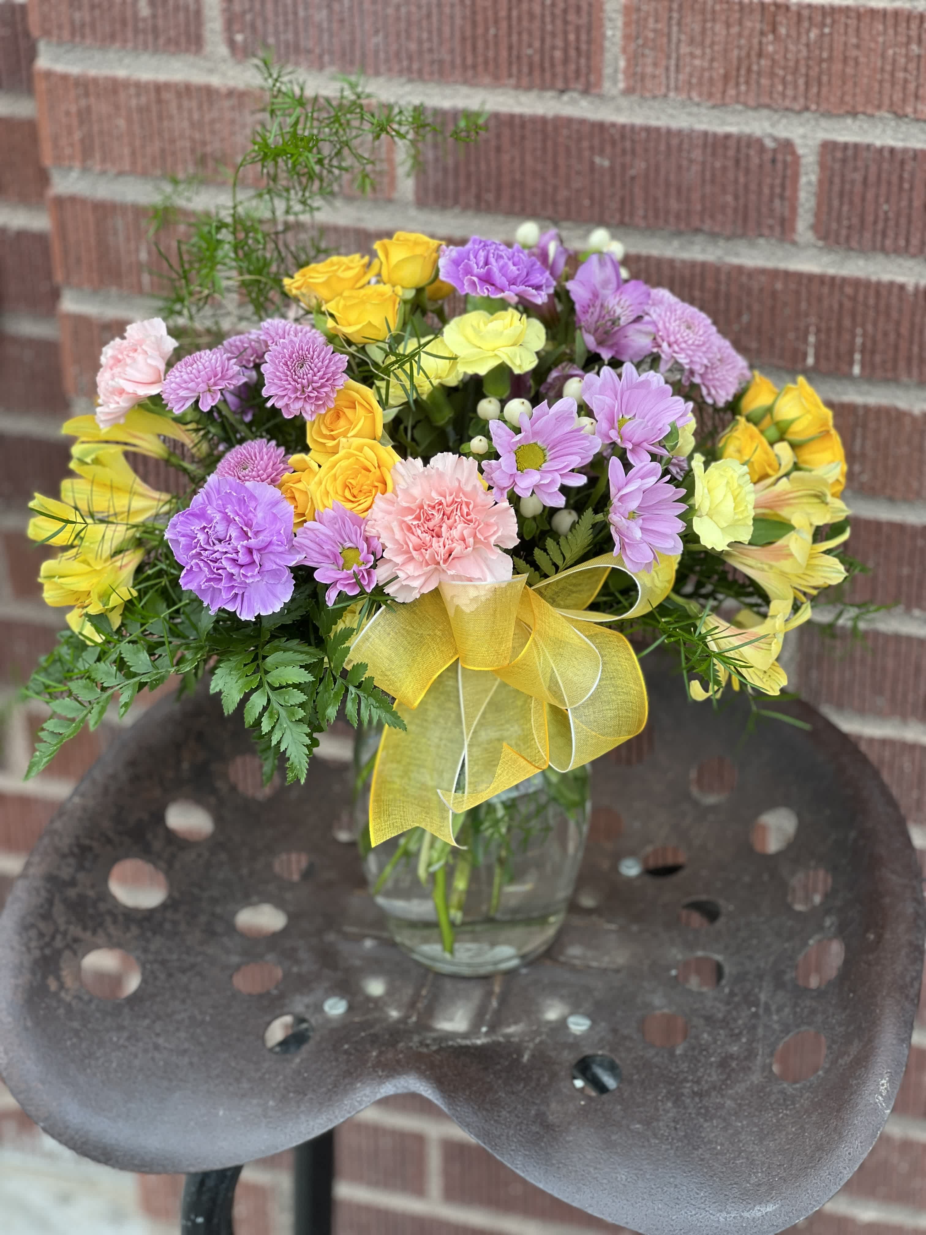 Colorful mixed bouquet in a clear glass vase with a yellow ribbon