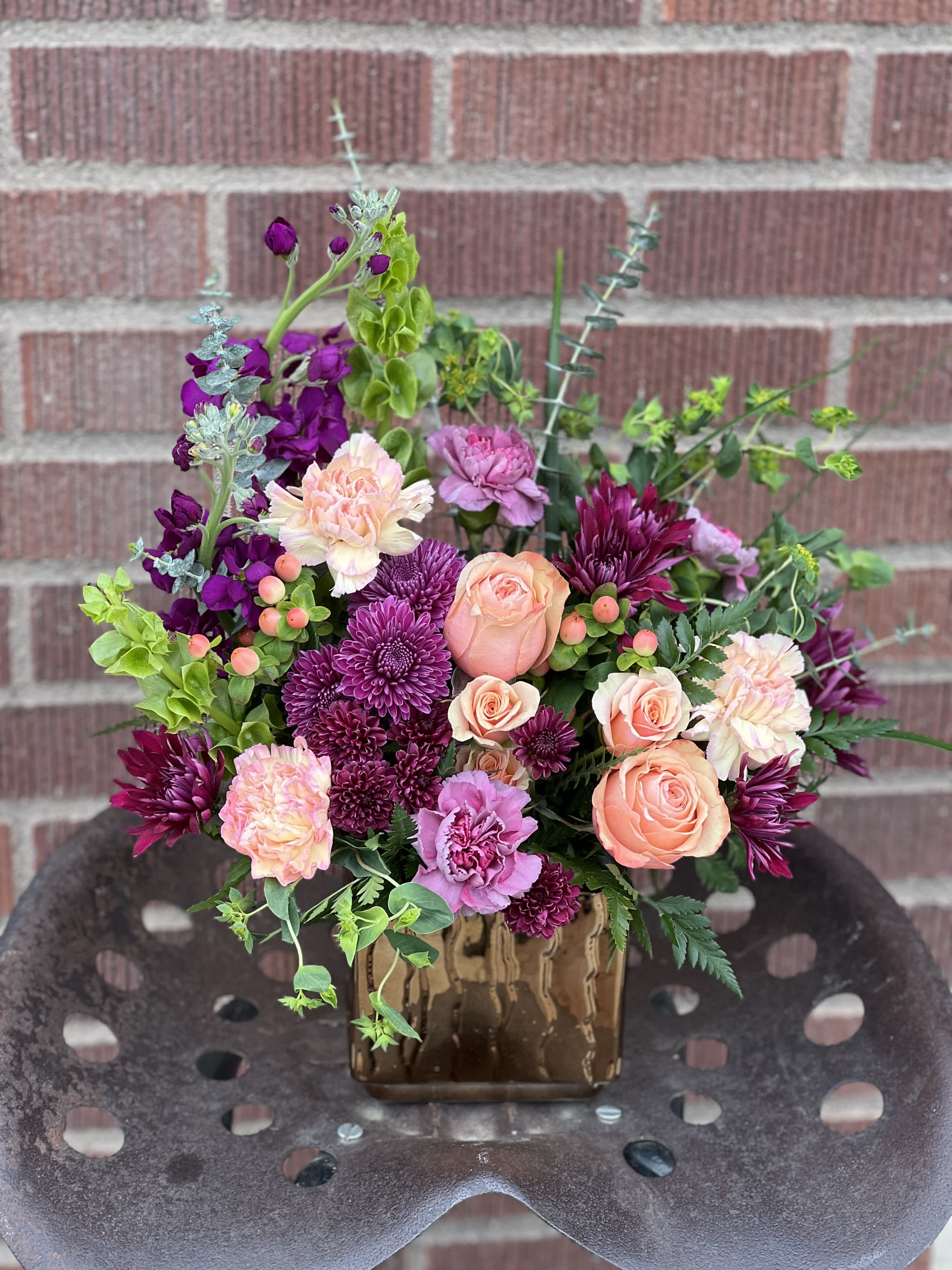 Mixed bouquet of peach, pink, and purple flowers in a brown vase