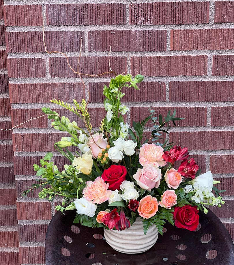 Mixed bouquet of roses, carnations, and white blooms in a white vase