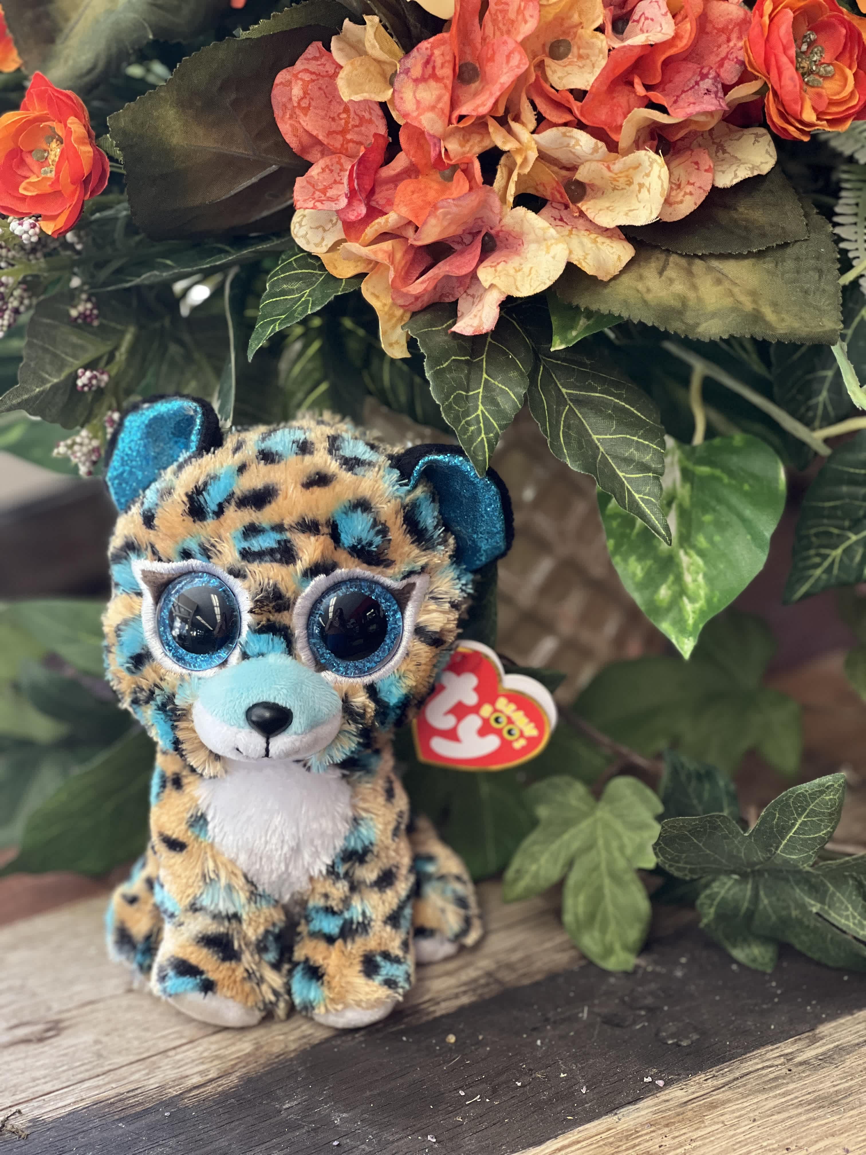 Plush leopard toy in front of an orange floral arrangement
