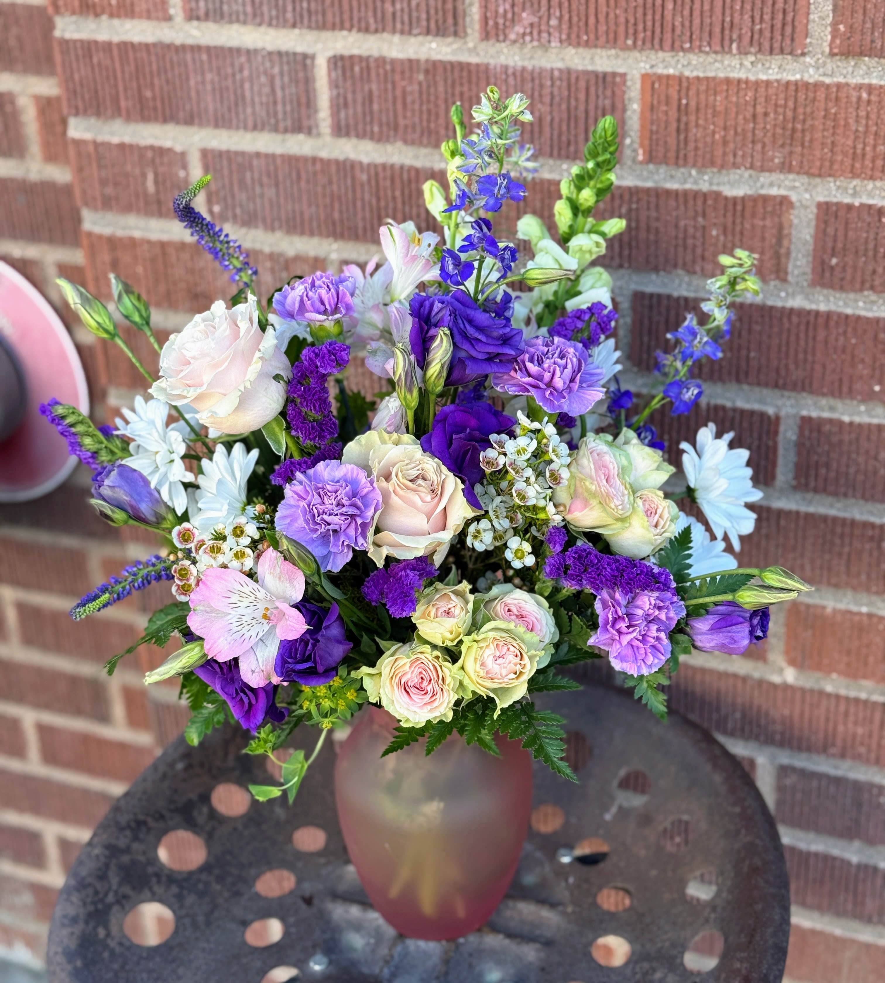 Bouquet of purple, pink, and white flowers in a frosted glass vase