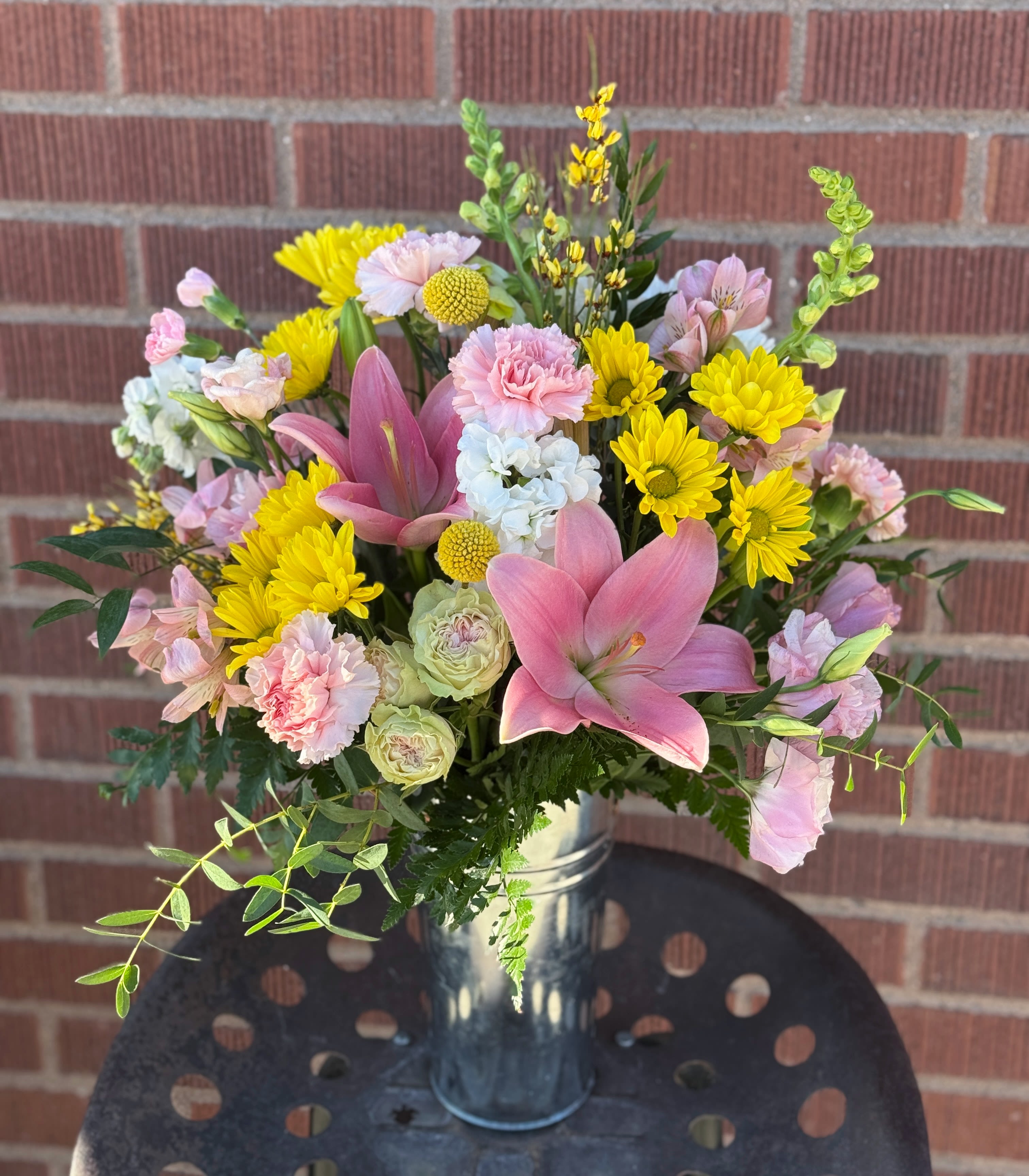 Pink lilies and yellow daisies in a metal vase