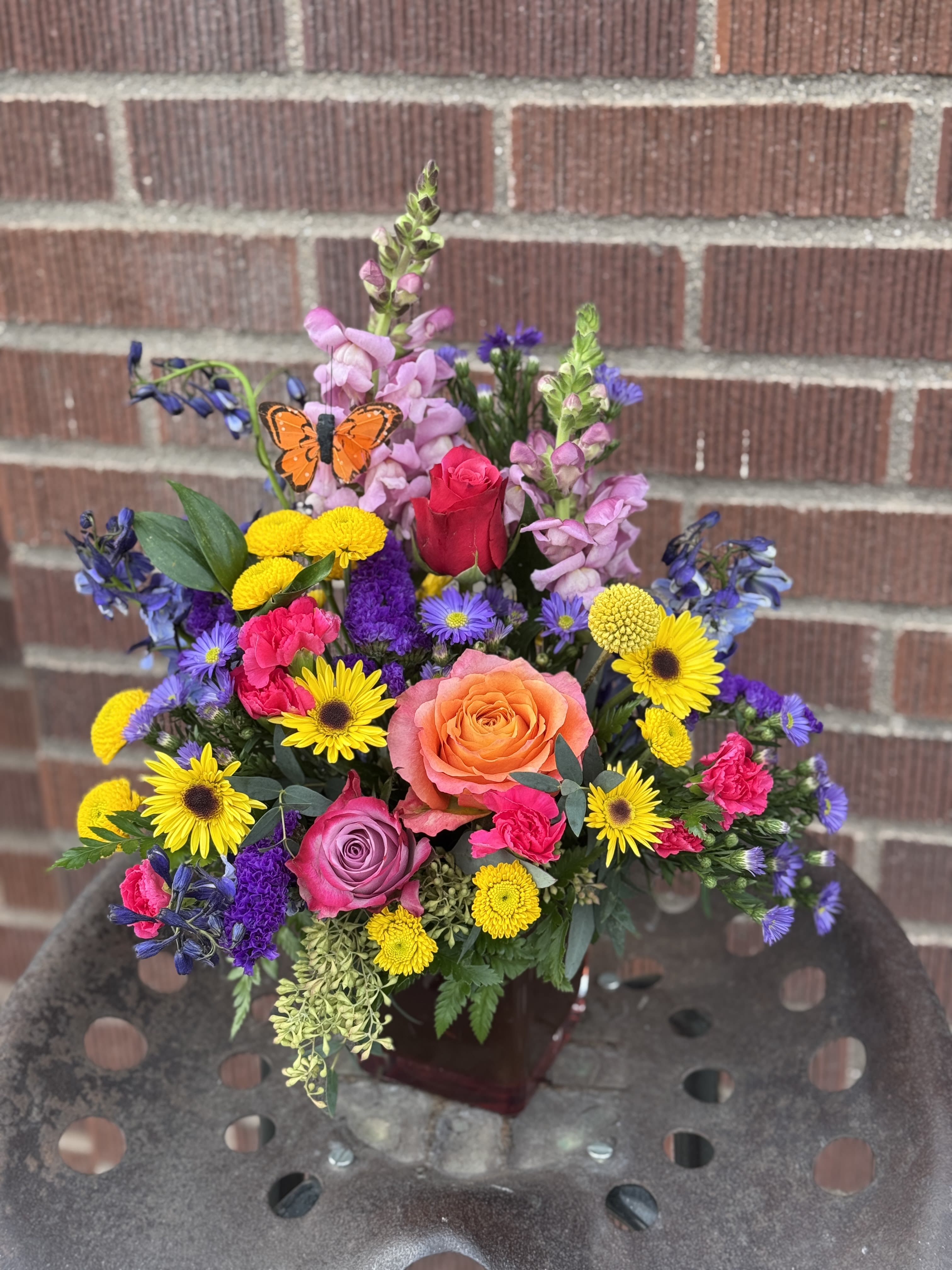Colorful mixed bouquet with roses, daisies, and snapdragons in a vase