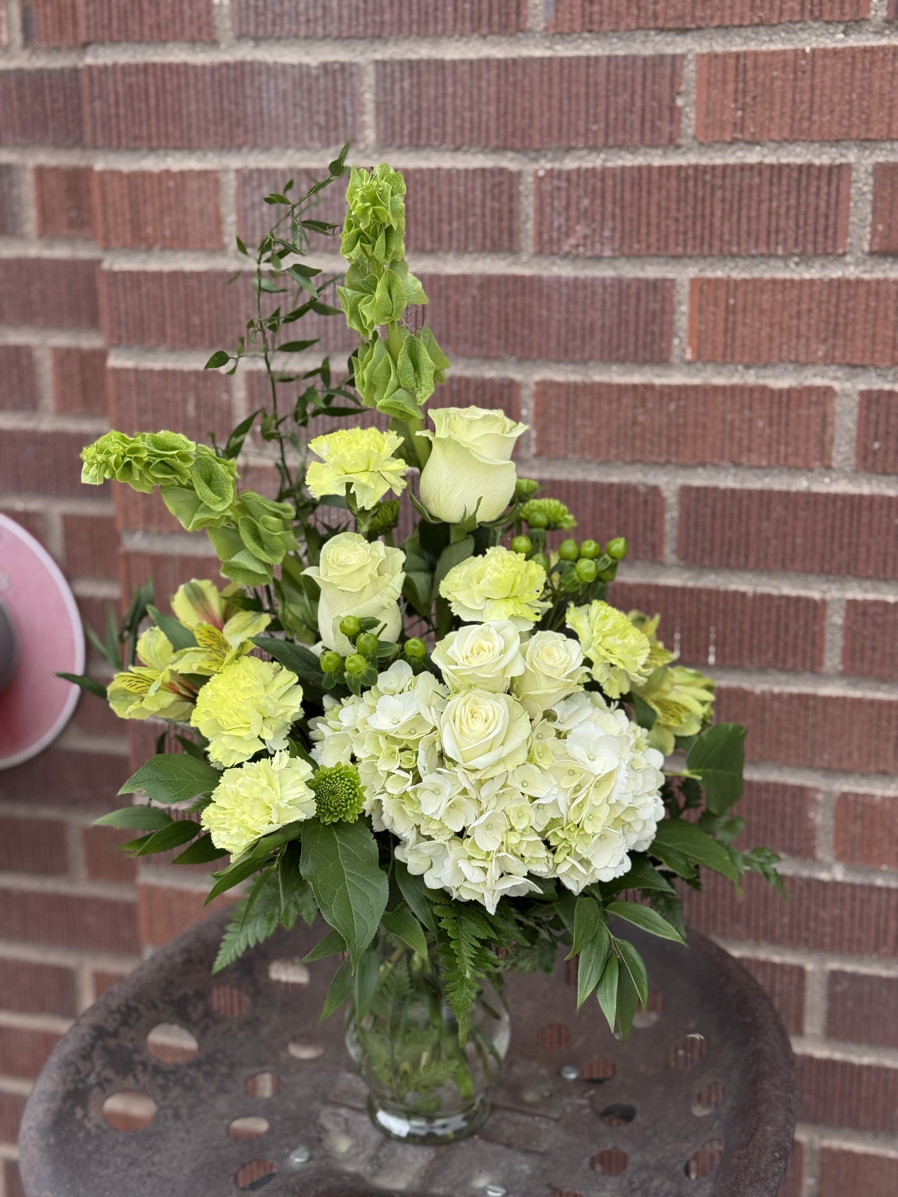 White and lime-green floral arrangement in a glass vase