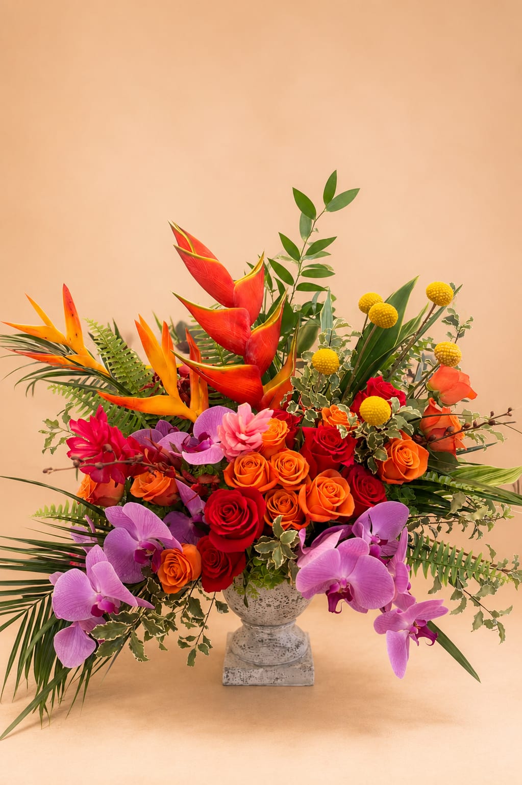 Happy Days  - Flowers: orange roses, pink roses, ginger, billy balls, heliconia, italian ruscus, phaelonopsis orchids, birds of paradise, and greenery.  Vase: grey stone compote large