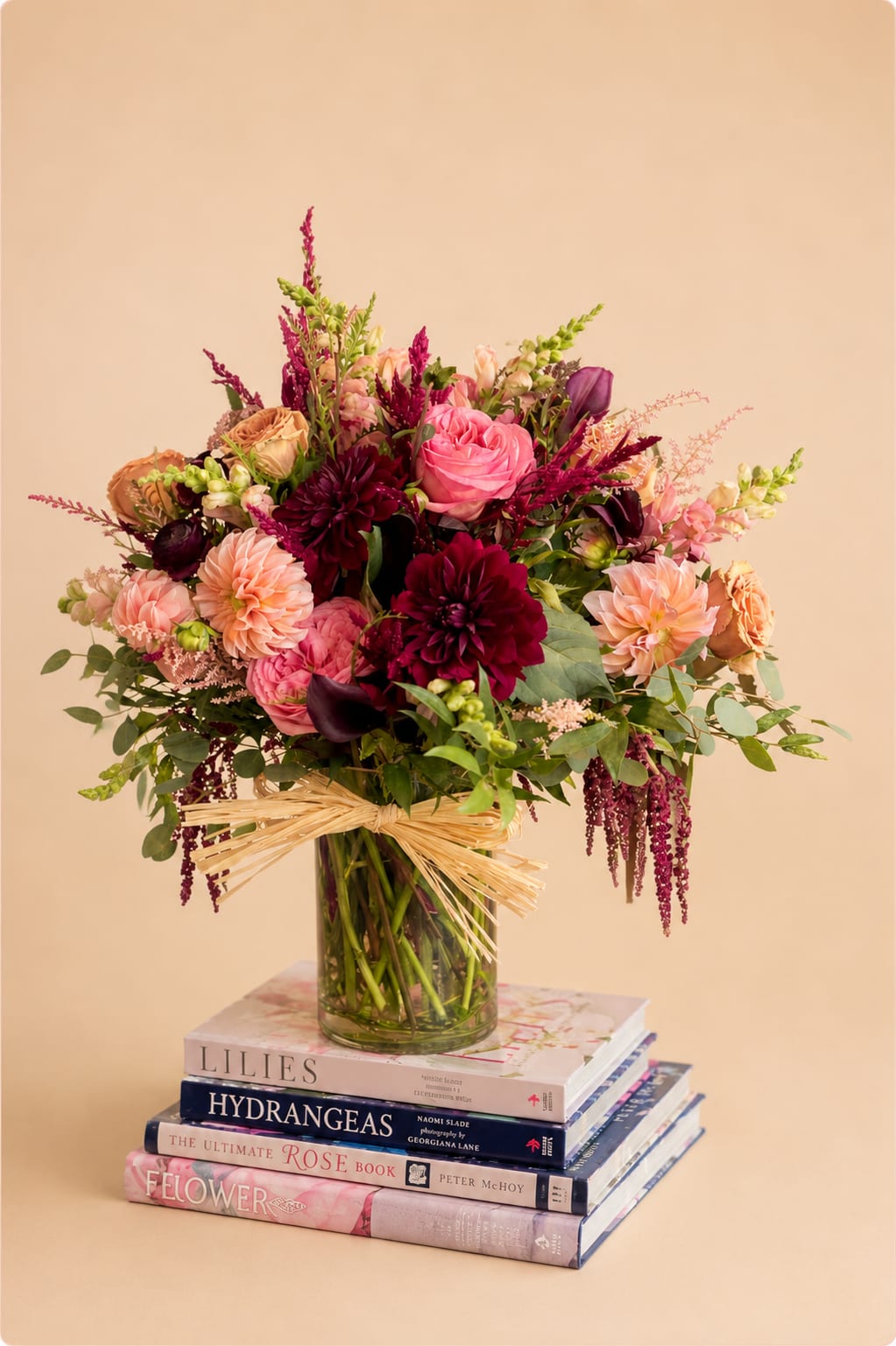 Countryside Kiss  - Flowers: pink xpression garden roses, burgundy dahlias, burgundy ranunculus, orange cream dahlias, toffee roses, dark purple calla lilies, pink snapdragon, astilbe, silver dollar eucalyptus, italian ruscus, and grevillea.  Arranged in a 6x8 glass vase adorned with a Rafia Bow  