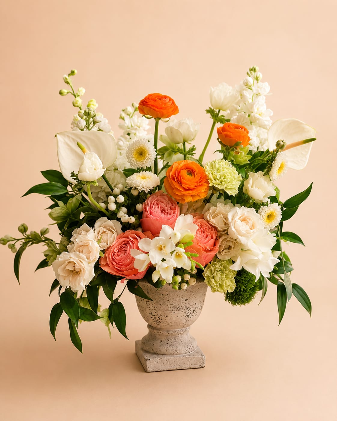 Fresh Summer  - Flowers: coral garden roses, ivory spray roses, white freesia, anemones, white hypericum, white stock, orange ranunculus, white anthurium, dianthus, green carnation, and italian ruscus.   Vase: medium size urn  One-Sided