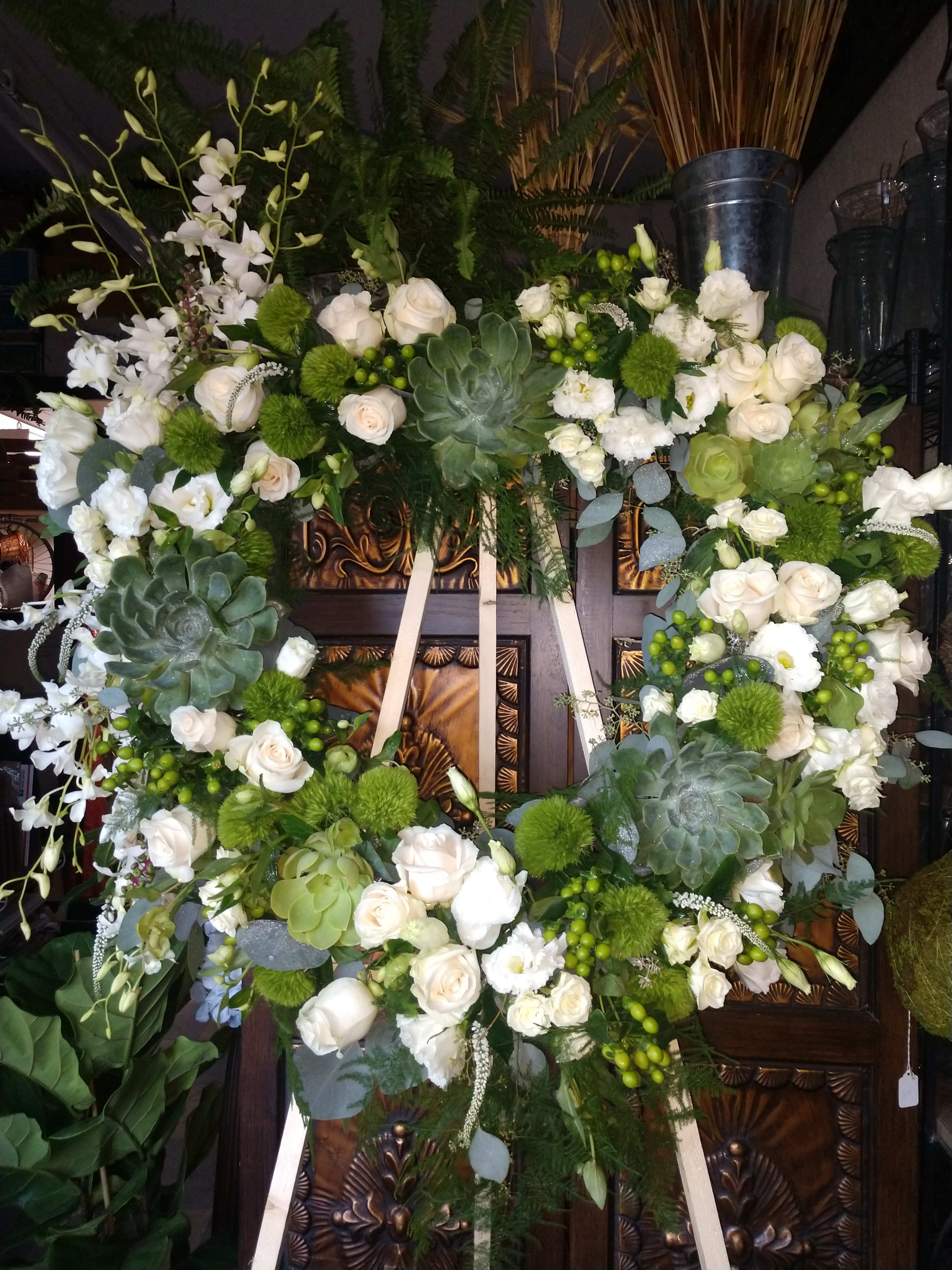 Large white floral wreath with roses and succulents on an easel