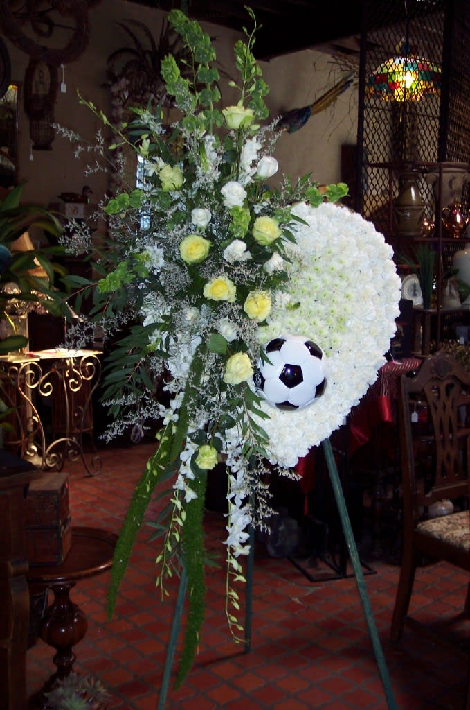 Standing floral tribute with white blooms and a soccer ball centerpiece