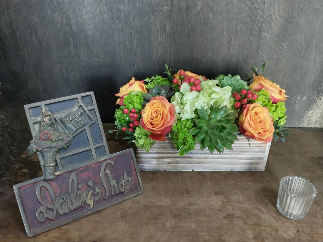Rectangular floral arrangement with orange roses and succulents in a wooden box