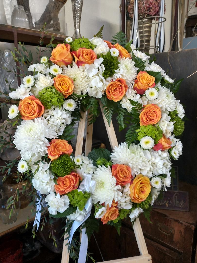 Heart-shaped floral wreath with orange roses and white chrysanthemums