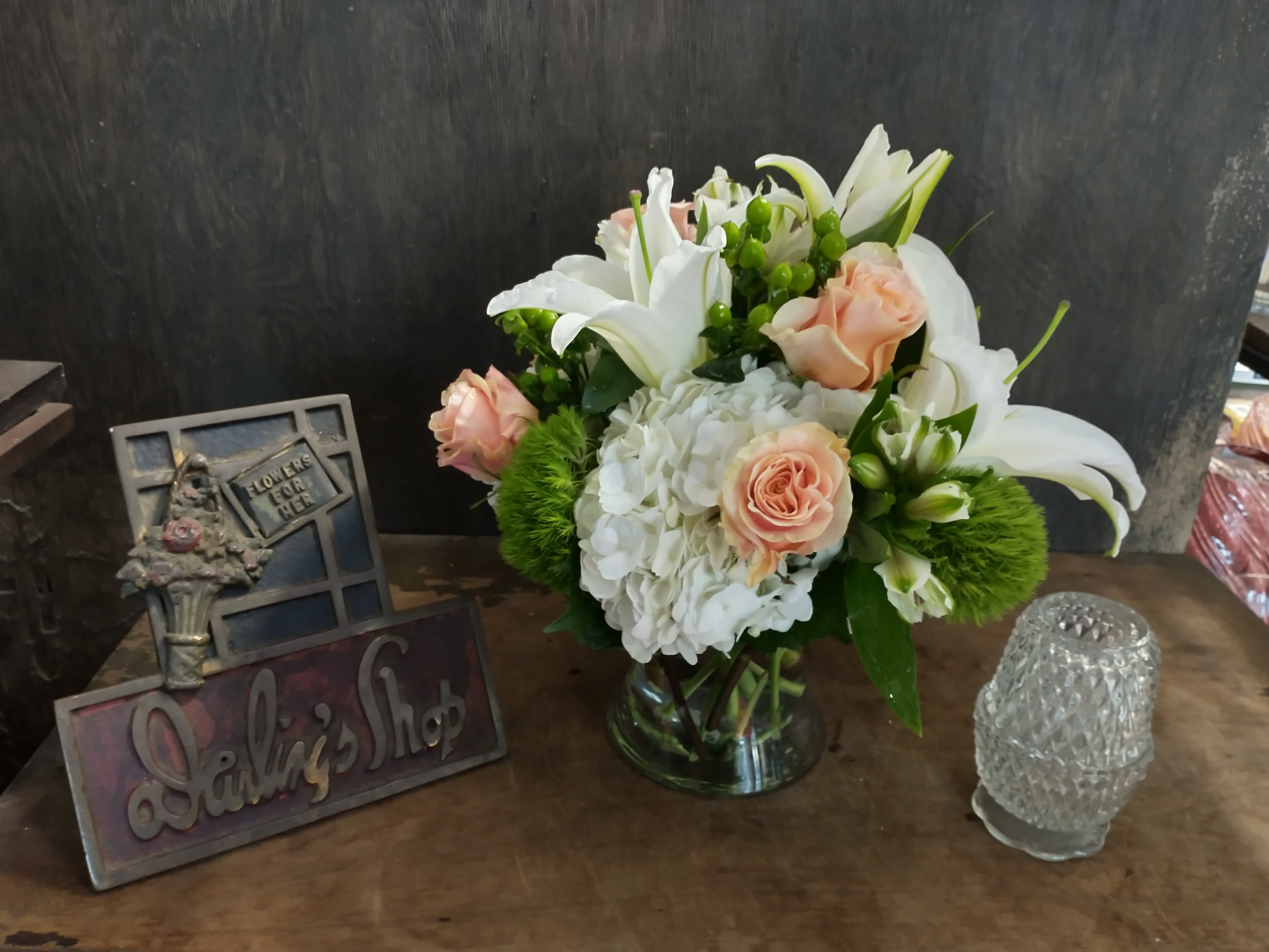 Bouquet of white lilies, peach roses, and white hydrangeas in a glass vase