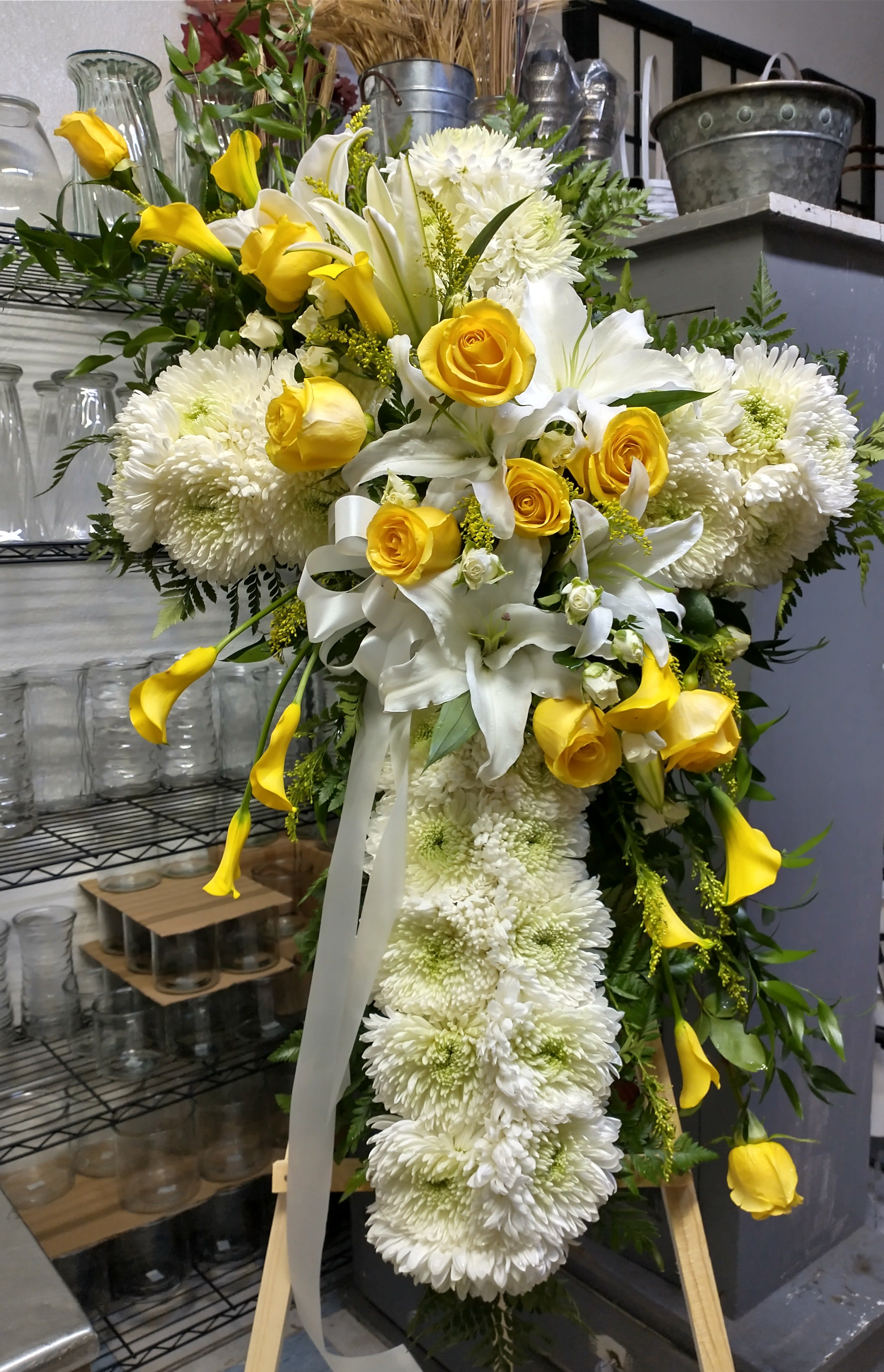 Large yellow and white floral standing spray with roses, lilies, and chrysanthemums