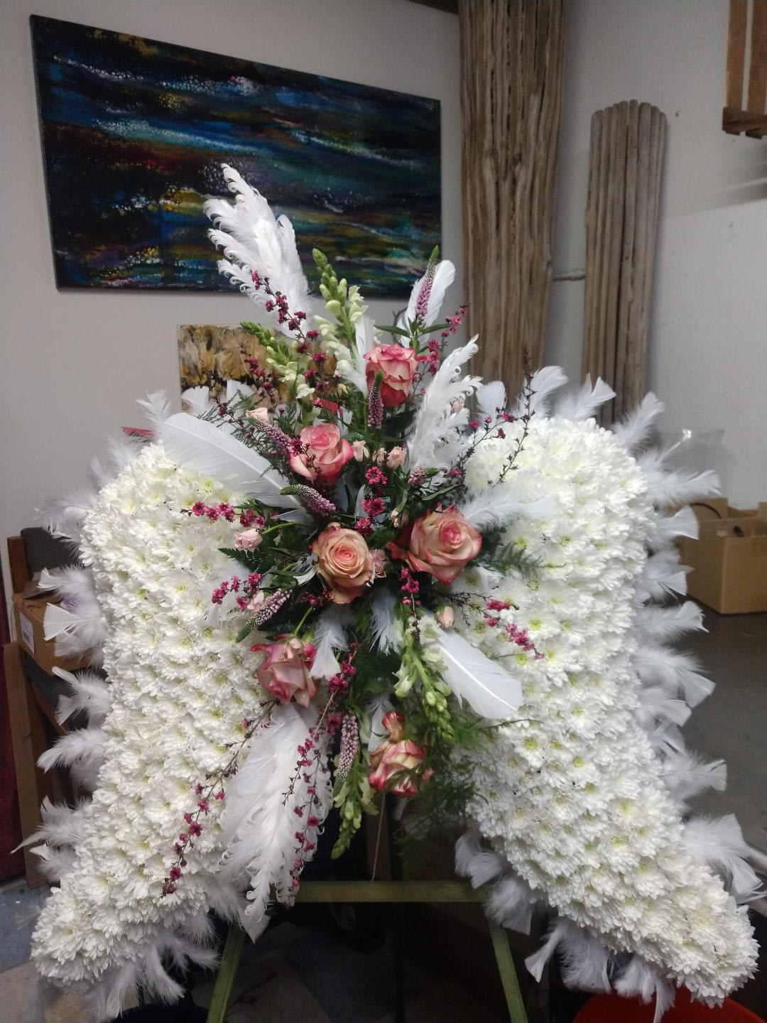 Large white floral standing spray with pink roses and white feathers