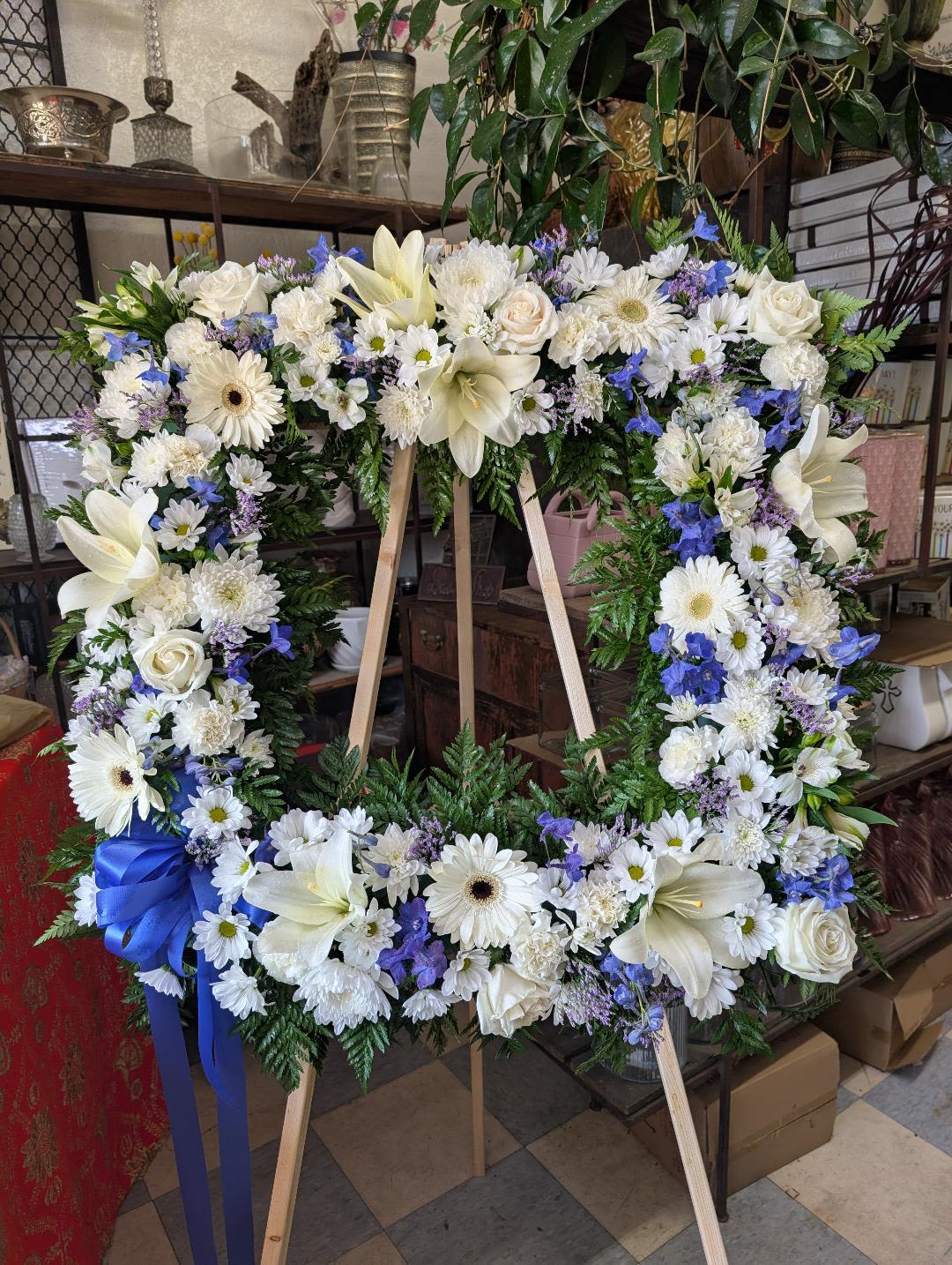 Large white and blue floral wreath on a wooden easel