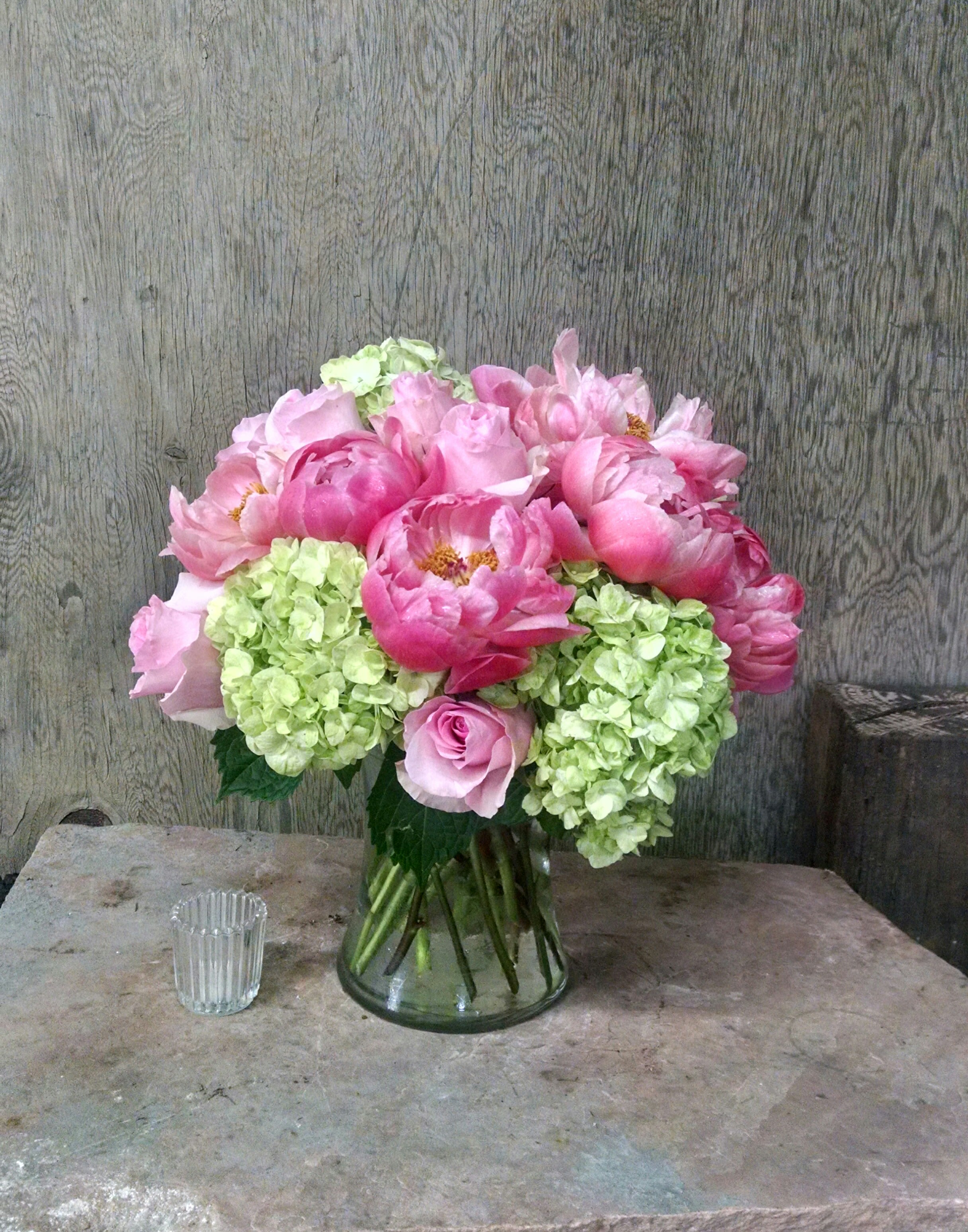 Pink peonies and green hydrangeas in a glass vase