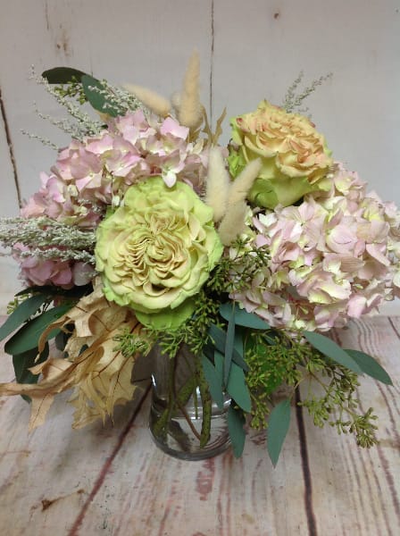 Pastel arrangement of green roses and pink hydrangeas in a clear glass vase