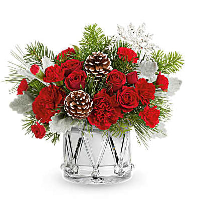 Red roses and carnations in a clear glass vase with pinecones and winter greenery