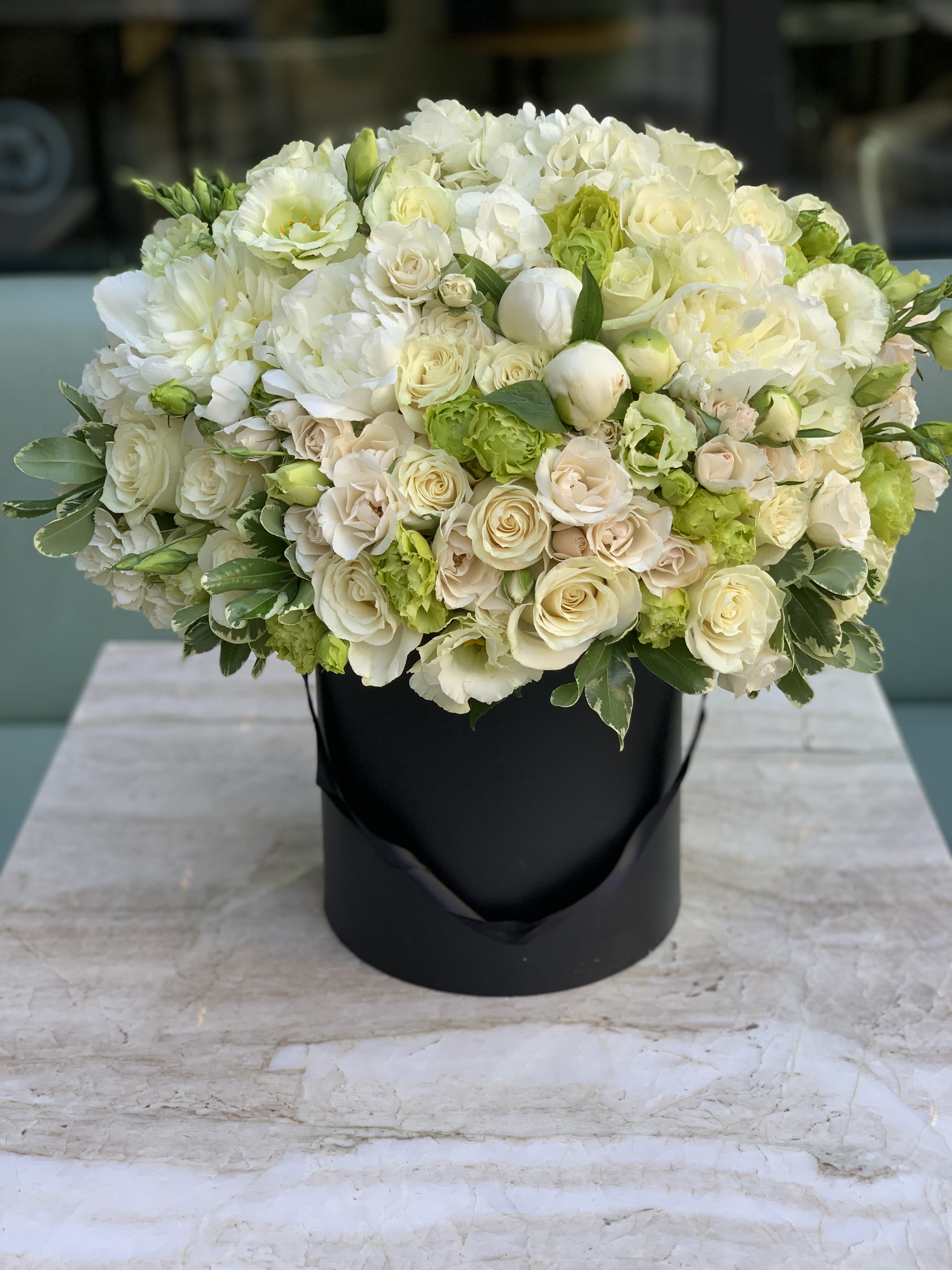 Elegant White &amp; Green Flower Arrangement - Elevate your gifting with a timeless and sophisticated arrangement, meticulously presented in our signature black hat box. This luxurious composition is a masterclass in texture and tone, featuring a delicate blend of premium white and soft cream roses, lush white peonies, airy hydrangeas, dainty spray roses, and hand-selected seasonal greenery.    As a premier Los Angeles florist, we understand that true elegance lies in the details. This soft white and green palette creates a refined, modern look that remains deeply classic—the perfect aesthetic for the discerning tastes of Beverly Hills, Santa Monica, and West Hollywood. Whether you are celebrating a milestone birthday, a romantic anniversary, or sending a "congratulations" to a colleague in Downtown LA, this arrangement serves as a stunning statement of grace.    Why Choose Our Boutique Floral Services?  Artisan Craftsmanship: Every arrangement is handcrafted by local experts to ensure beauty, fullness, and a high-end finish.    Unmatched Quality: we source the freshest blooms daily to ensure long-lasting freshness and vibrant life.    Reliable Delivery: We offer premier flower delivery in Los Angeles, serving neighborhoods from Pasadena to Malibu with professional care.    Transform any occasion into an unforgettable memory with a gift that embodies the luxury of the city. When you need a florist in Los Angeles that prioritizes quality and style, our signature collection is the ultimate choice.