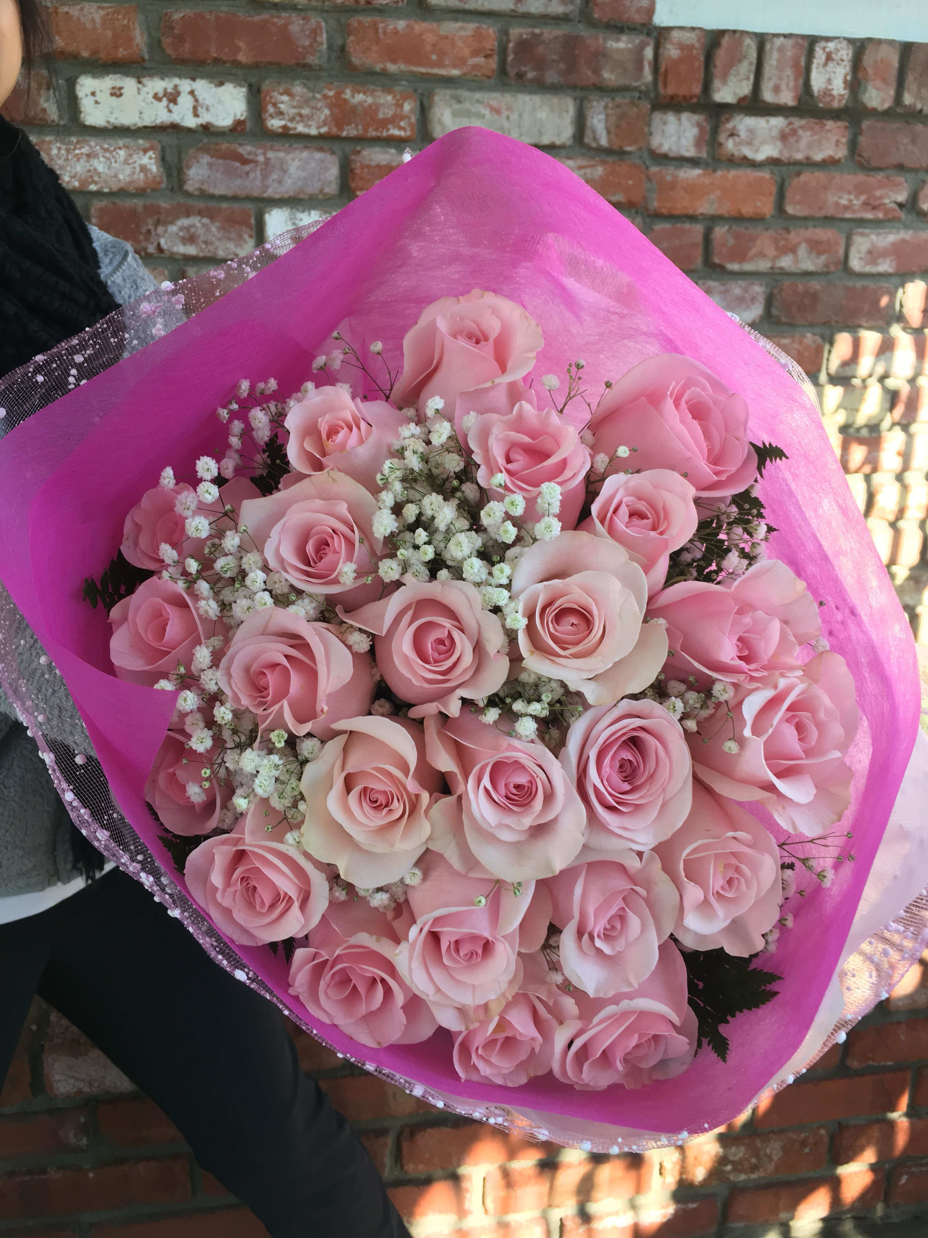 Bouquet of pale pink roses with baby's breath in bright pink wrap