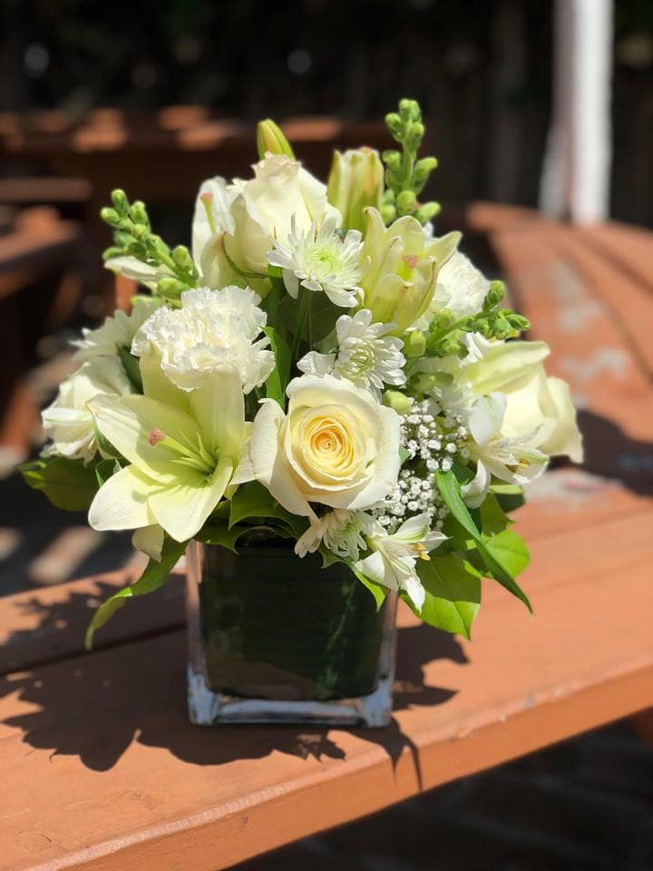 White floral arrangement in a square glass vase