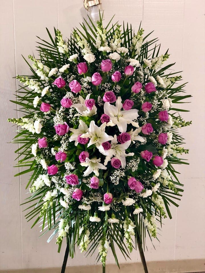Standing floral spray with pink roses and white lilies on a black easel