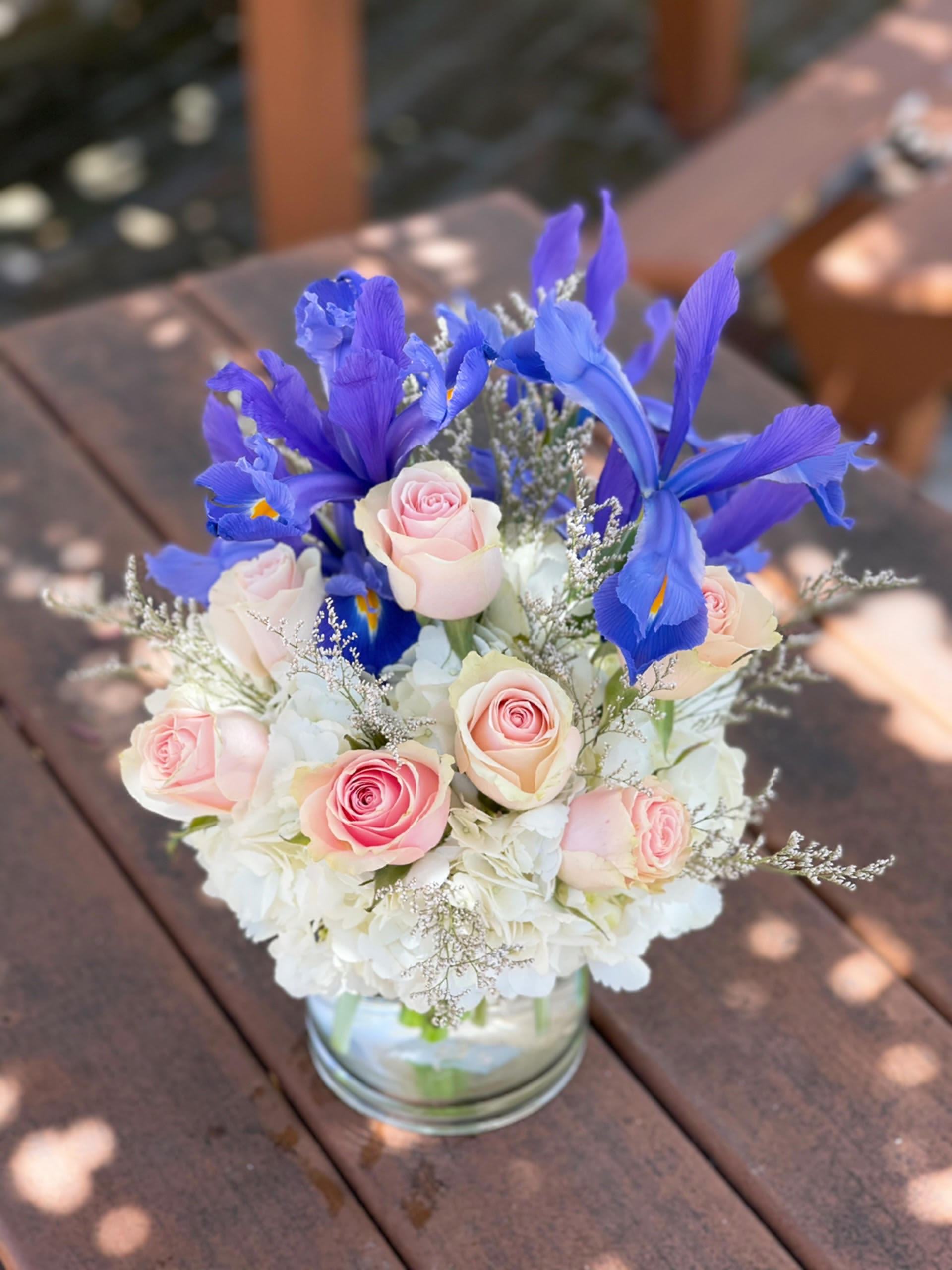 Pink roses and blue irises arranged in a glass vase