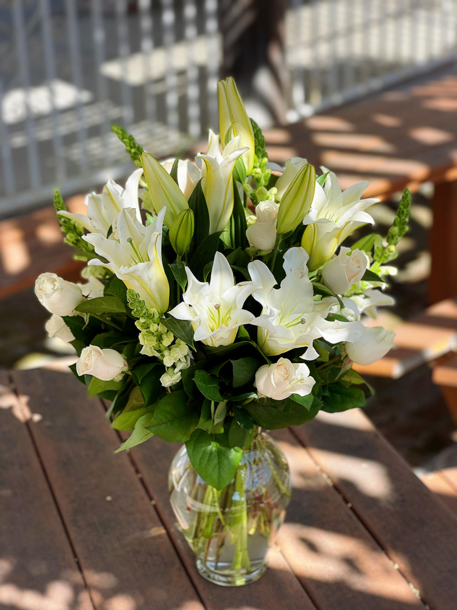 White lilies and pale roses arranged in a clear glass vase