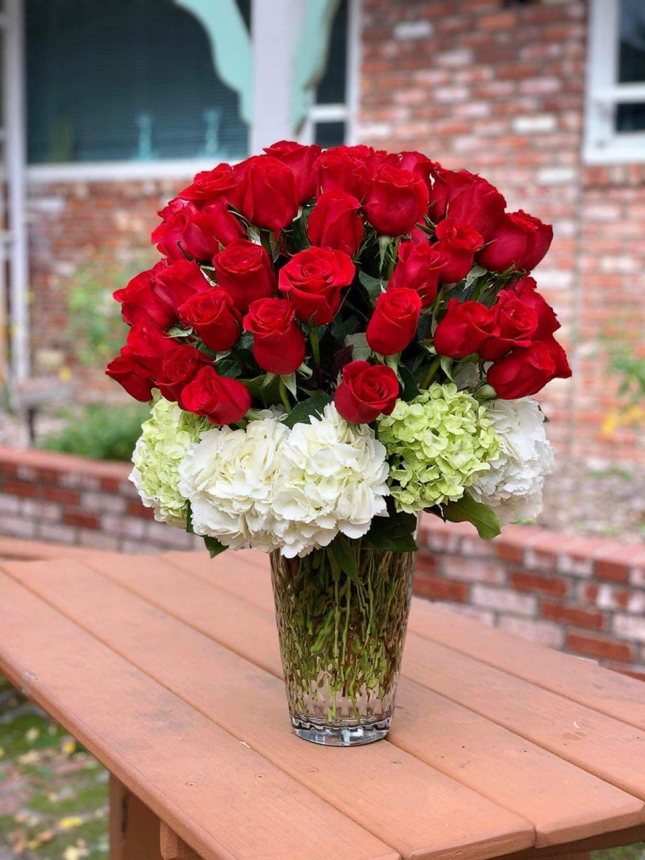 Red roses and white hydrangeas arranged in a clear glass vase