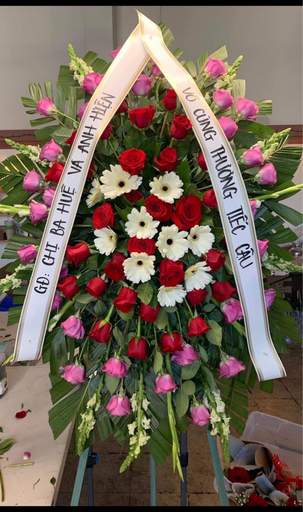 Large funeral wreath of red and pink roses with white daisies and ribbons