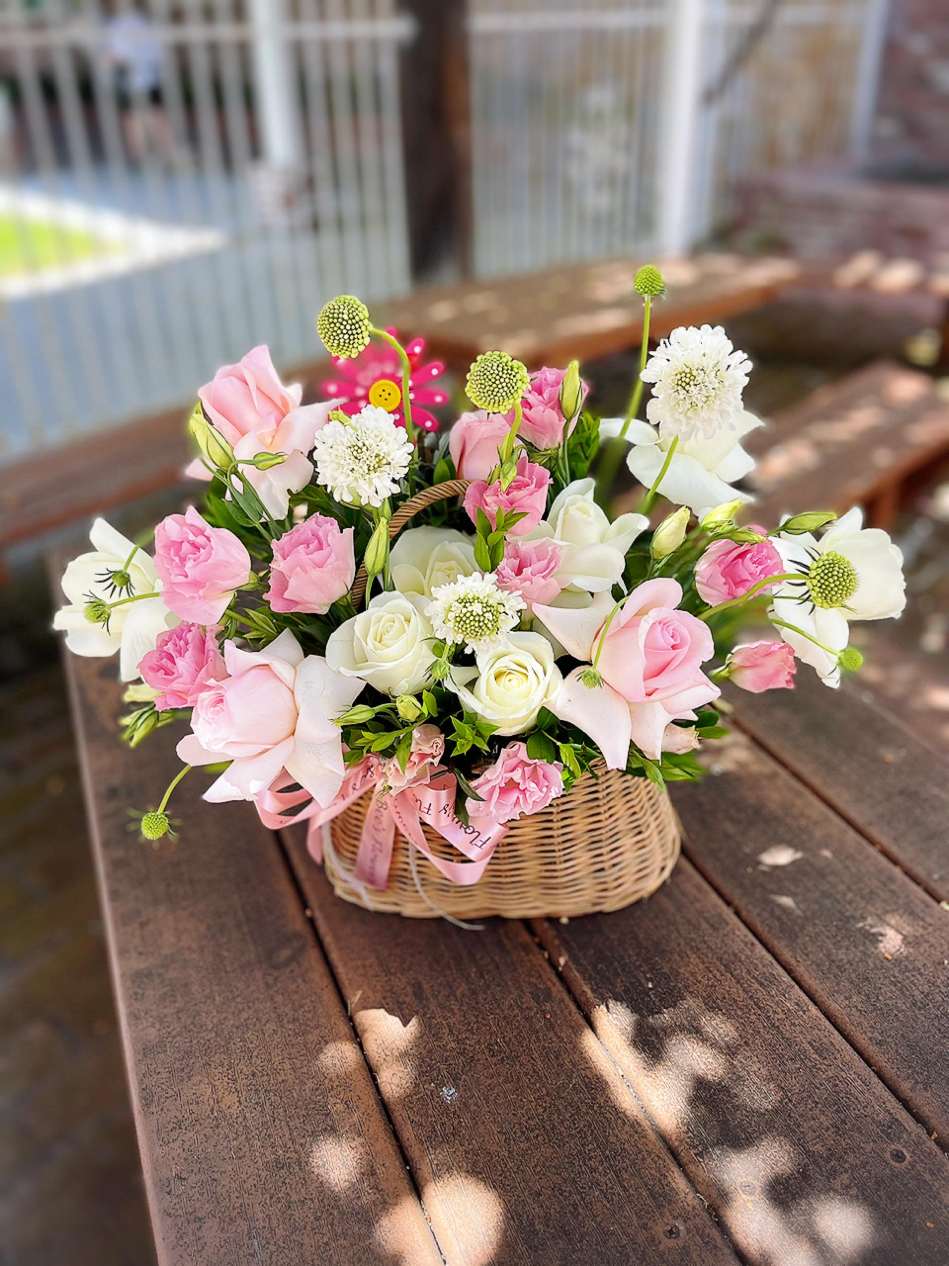 Pink and white flowers arranged in a wicker basket