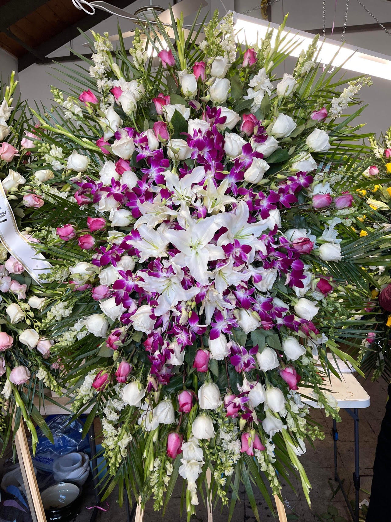 Large standing floral spray with white lilies, pink roses, and purple orchids