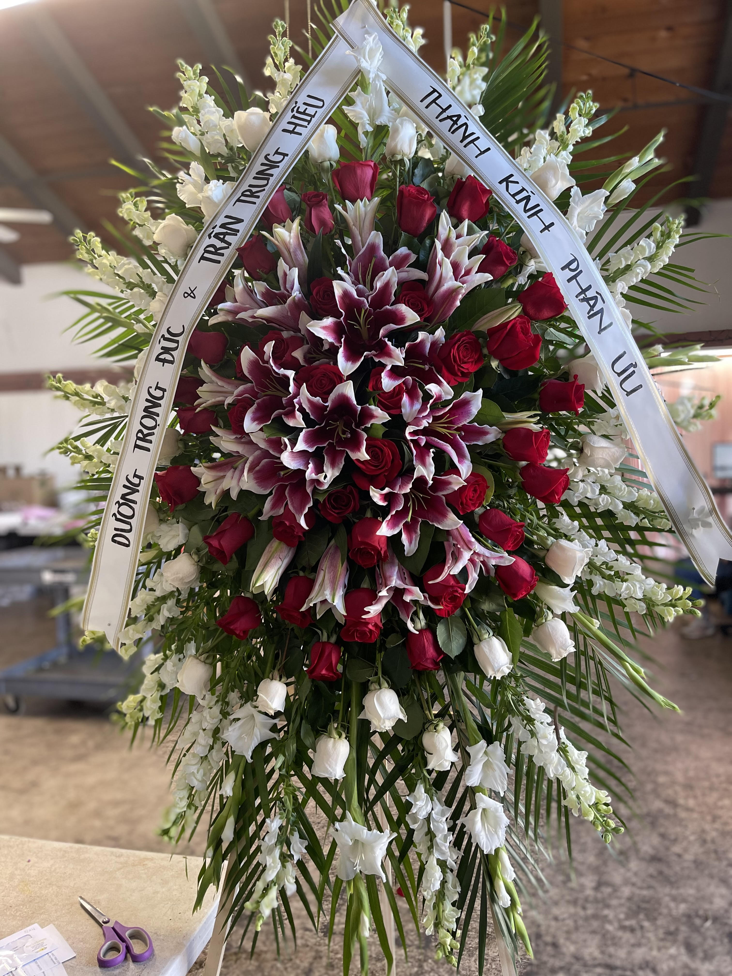 Large funeral wreath of red roses and white lilies with condolence ribbons