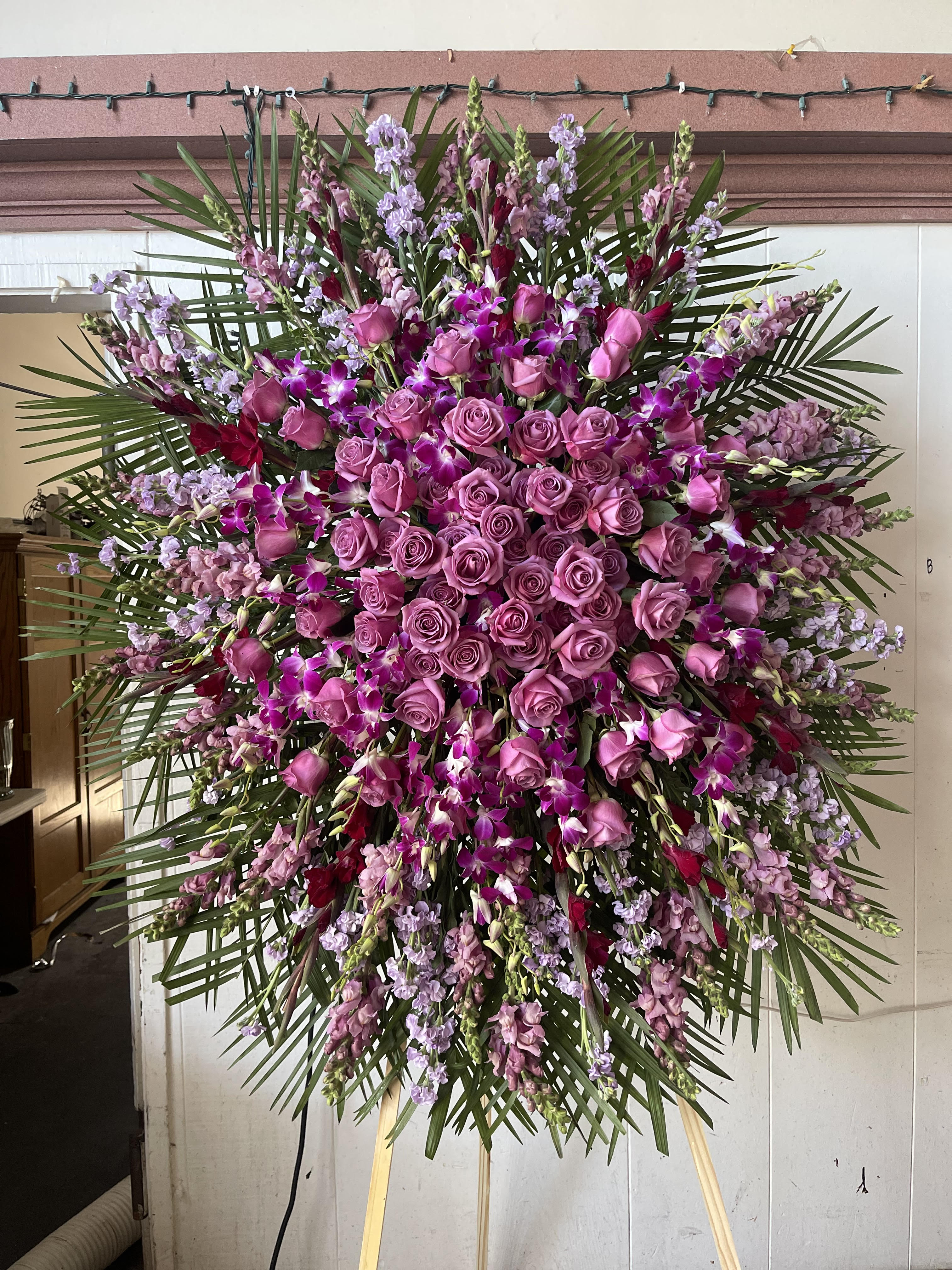 Large standing spray of pink roses and purple orchids with palm fronds