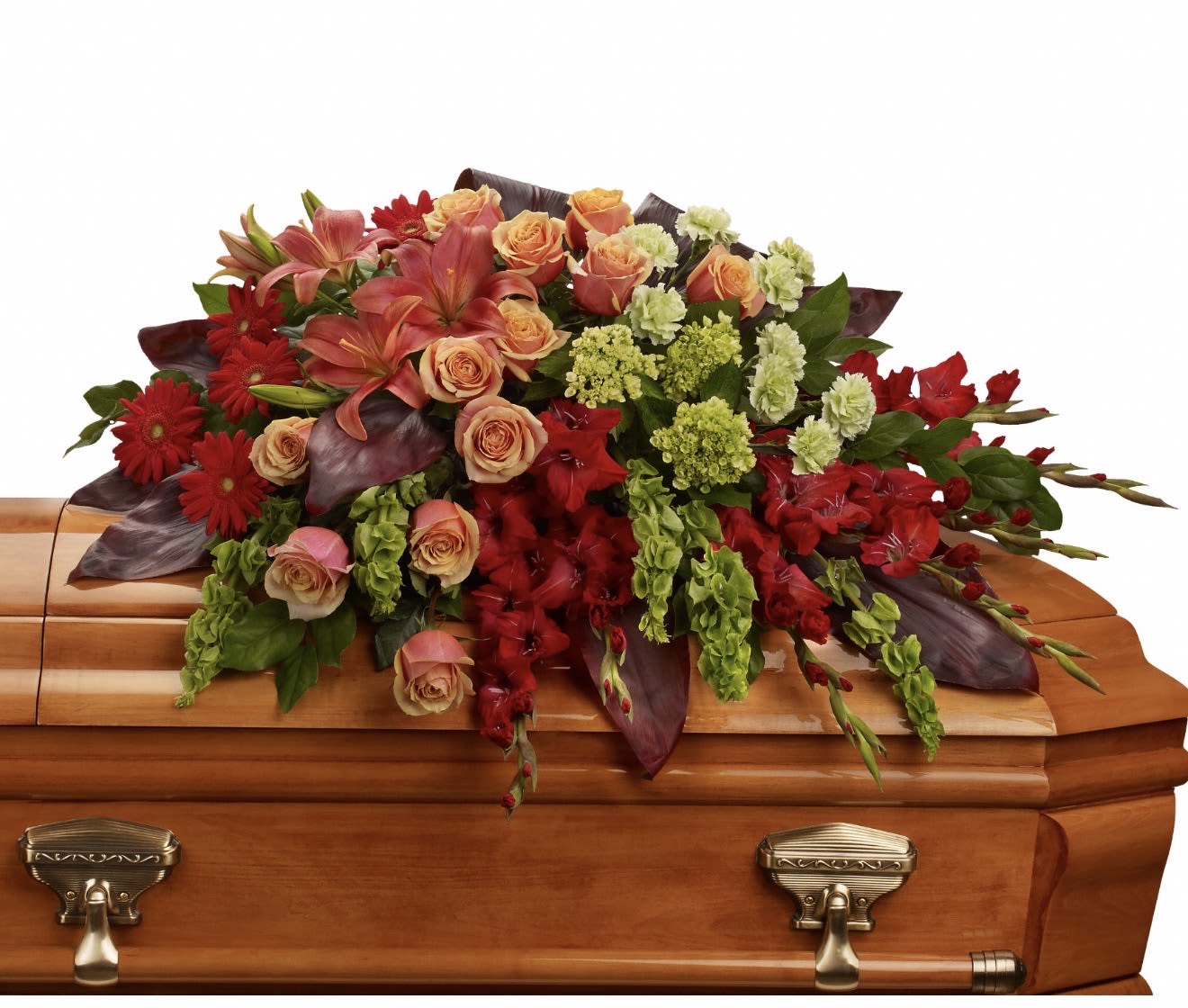 A Fond Farewell Casket Spray - A Fond Farewell offers a richly layered sympathy arrangement designed to convey deep respect and gentle remembrance. This funeral spray features striking red gerbera daisies and deep red blooms paired with soft peach roses and pink lilies, creating a warm, comforting palette ideal for a memorial service or to honor a loved one's passing. Dark burgundy foliage and pale green filler clusters add contrast and depth, giving the design a formal, dignified presence.  The composition is large and cascading, arranged to present a full, sculpted silhouette with layered textures-from the smooth petals of roses and lilies to the bold centers of gerberas and the soft spray of filler flowers. Colors include red, pink, peach, and green; materials include roses, lilies, gerbera daisies, carnations and complementary seasonal florals. This arrangement is crafted to provide a meaningful, respectful tribute that will help the person you're honoring feel remembered and celebrated. Shipping and sizing details are available at checkout.