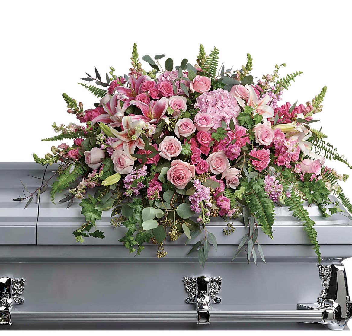 Beautiful Memories Casket Spray - A lush cascade of soft pink roses and pale pink lilies creates a tender, dignified focal point for a sympathy or funeral service. This casket spray is designed for memorials and services, the kind of floral tribute that gently announces love and remembrance while reflecting a preference for pink tones.  The arrangement features densely clustered pink roses, pale pink lilies, carnations and complementary pink blooms arranged across a silver casket base, with eucalyptus and fern-like foliage woven through to add texture and graceful movement. The palette of pink, white and green reads soft and feminine; the overall design spreads broadly to cover the top of the casket and offers a formal, polished presentation appropriate for honoring a loved one.  Thoughtfully composed to convey comfort and lasting memory, this spray is meant for the person you're remembering-she'll feel seen and cherished in a quiet, elegant way. Please confirm casket size and service timing when ordering so we can ensure proper fit and delivery for the memorial.