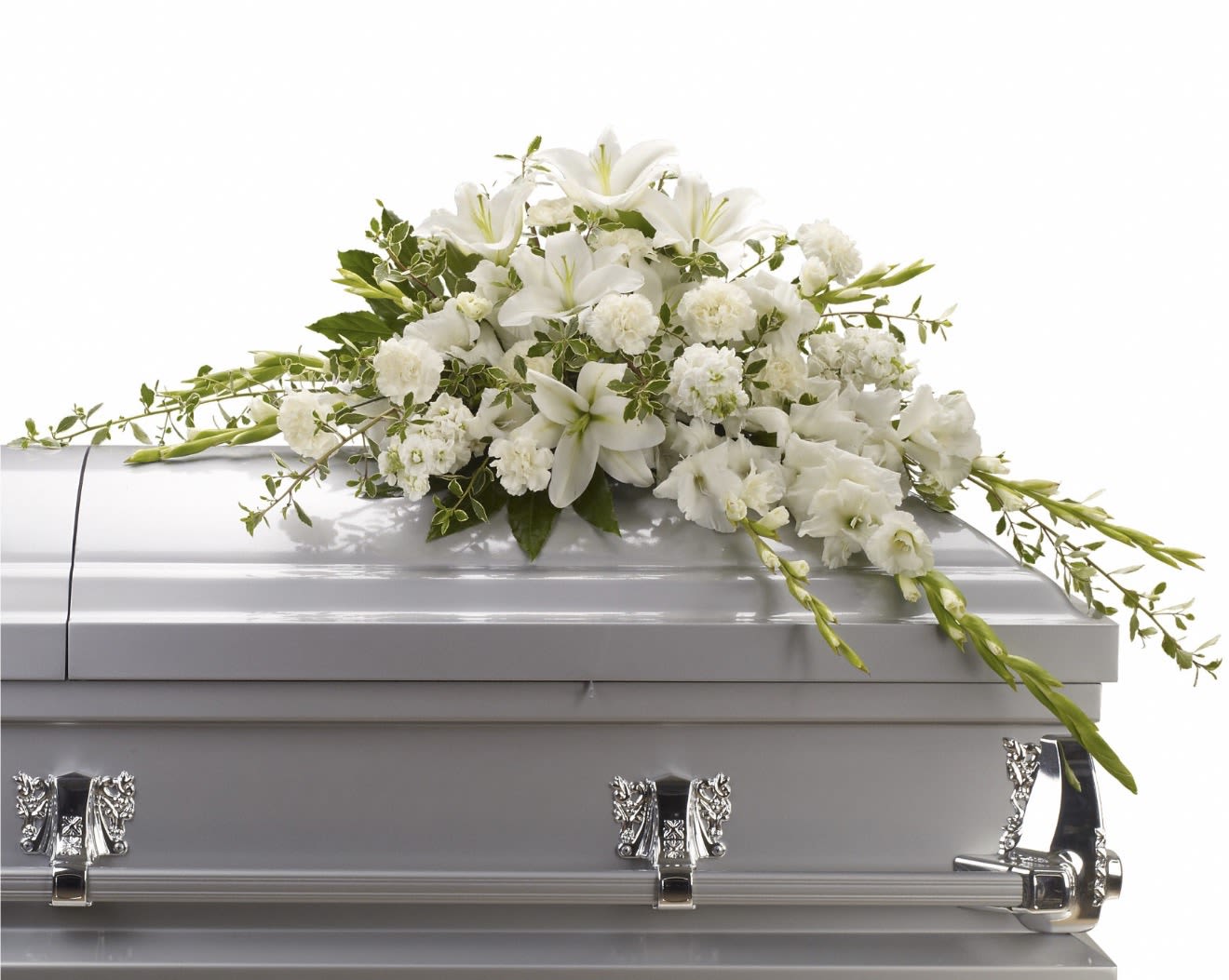Bountiful Memories Casket Spray - Pure white lilies take center stage in this sympathy spray, creating a tranquil, reverent impression meant to comfort the person you're honoring. Designed for memorial and sympathy moments, the arrangement's soft white and green palette and layered silhouette convey calm dignity and respect.  Clusters of white carnations and delicate lisianthus surround the focal lilies, while airy trailing accents add gentle movement and texture. Set against a silver base, the composition is formal yet tender-measuring to fit traditional memorial presentations and crafted for a lasting visual presence.  This is a thoughtful way to express sympathy and remembrance for family, friends, or a cherished colleague; it offers a serene, consoling display that helps say "you're in our thoughts." Carefully arranged by our florists, it arrives ready for placement-no additional assembly required.