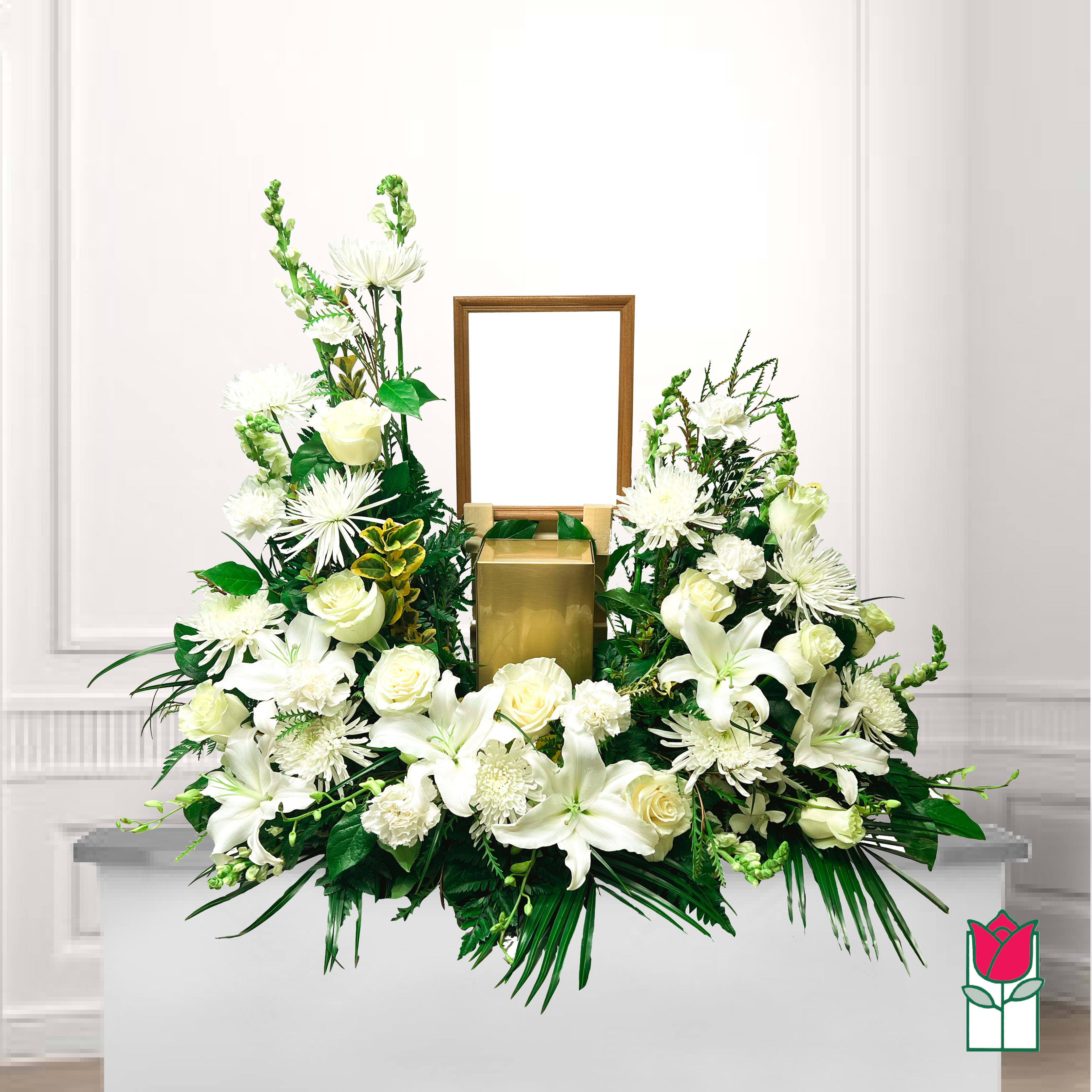 White floral funeral arrangement with a gold urn and empty frame