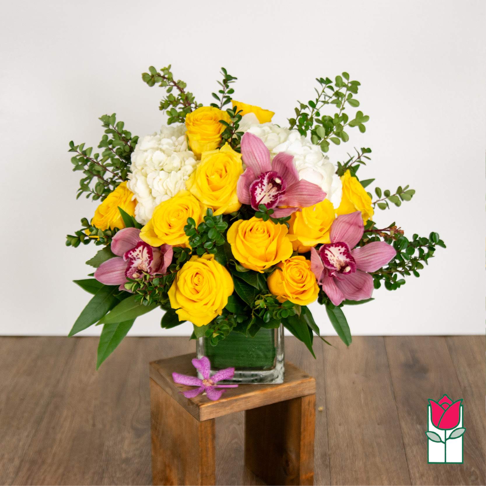 Yellow roses and pink orchids in a glass vase