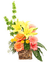 Mixed bouquet in a woven basket with yellow lilies and orange roses
