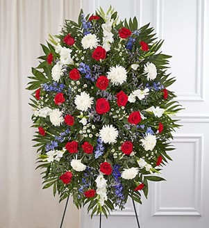 Standing funeral spray with red roses, white chrysanthemums, and blue flowers