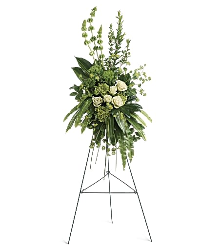 Tall green and white standing spray with roses and Bells of Ireland on a black metal easel