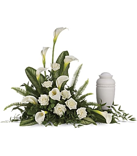 White calla lilies and roses arranged around a white cremation urn.
