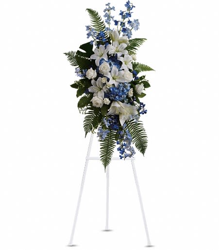Tall white and blue standing spray with lilies and roses on a white easel
