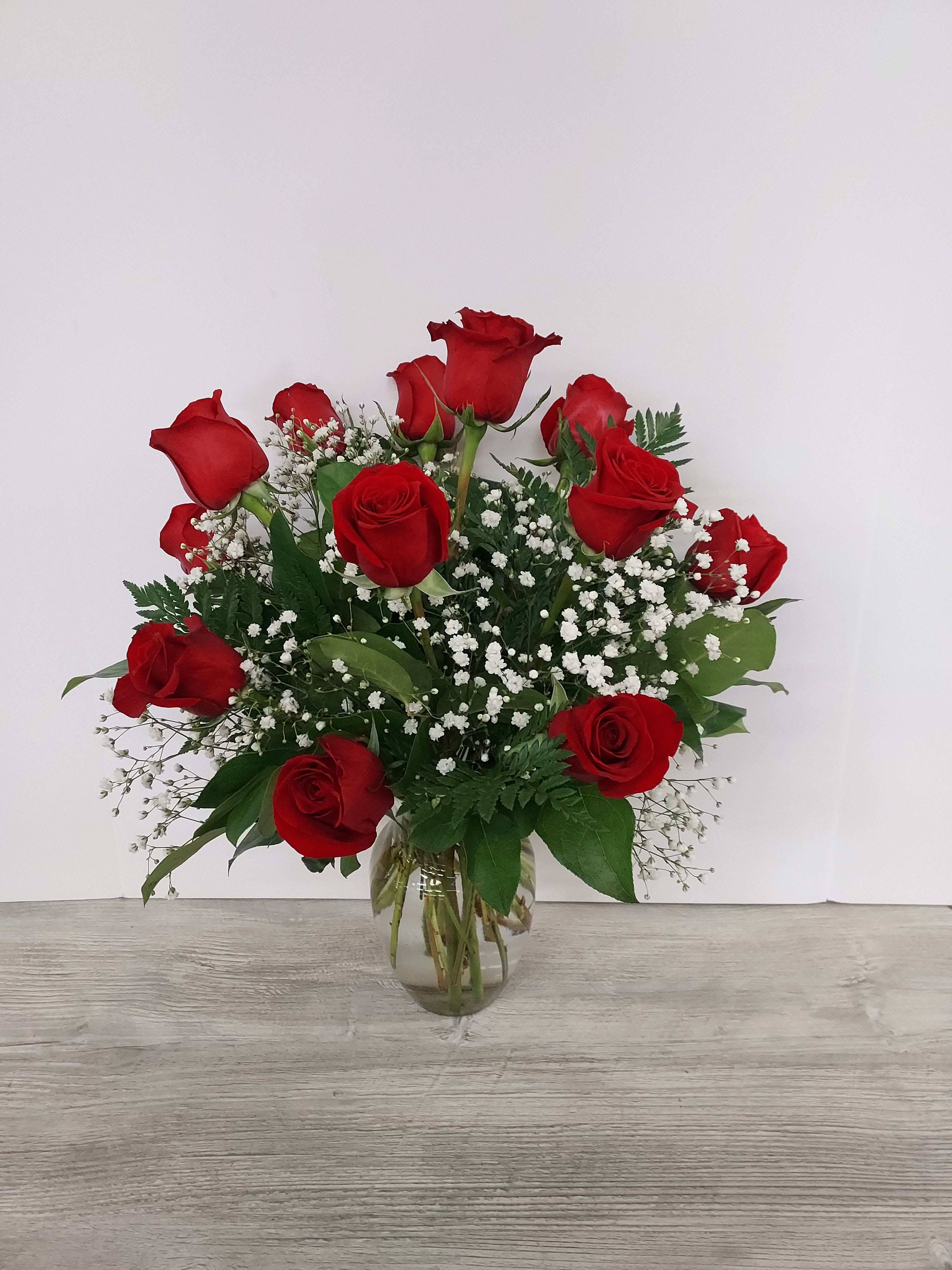 Arrangement of red roses with white filler flowers in a clear glass vase
