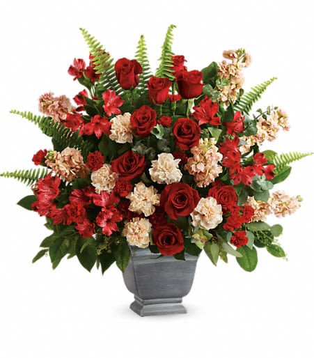 Large red and cream flower arrangement in a gray urn-style vase