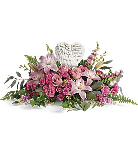 Pink lily and rose sympathy arrangement with angel-wing memorial stone in a low horizontal design.