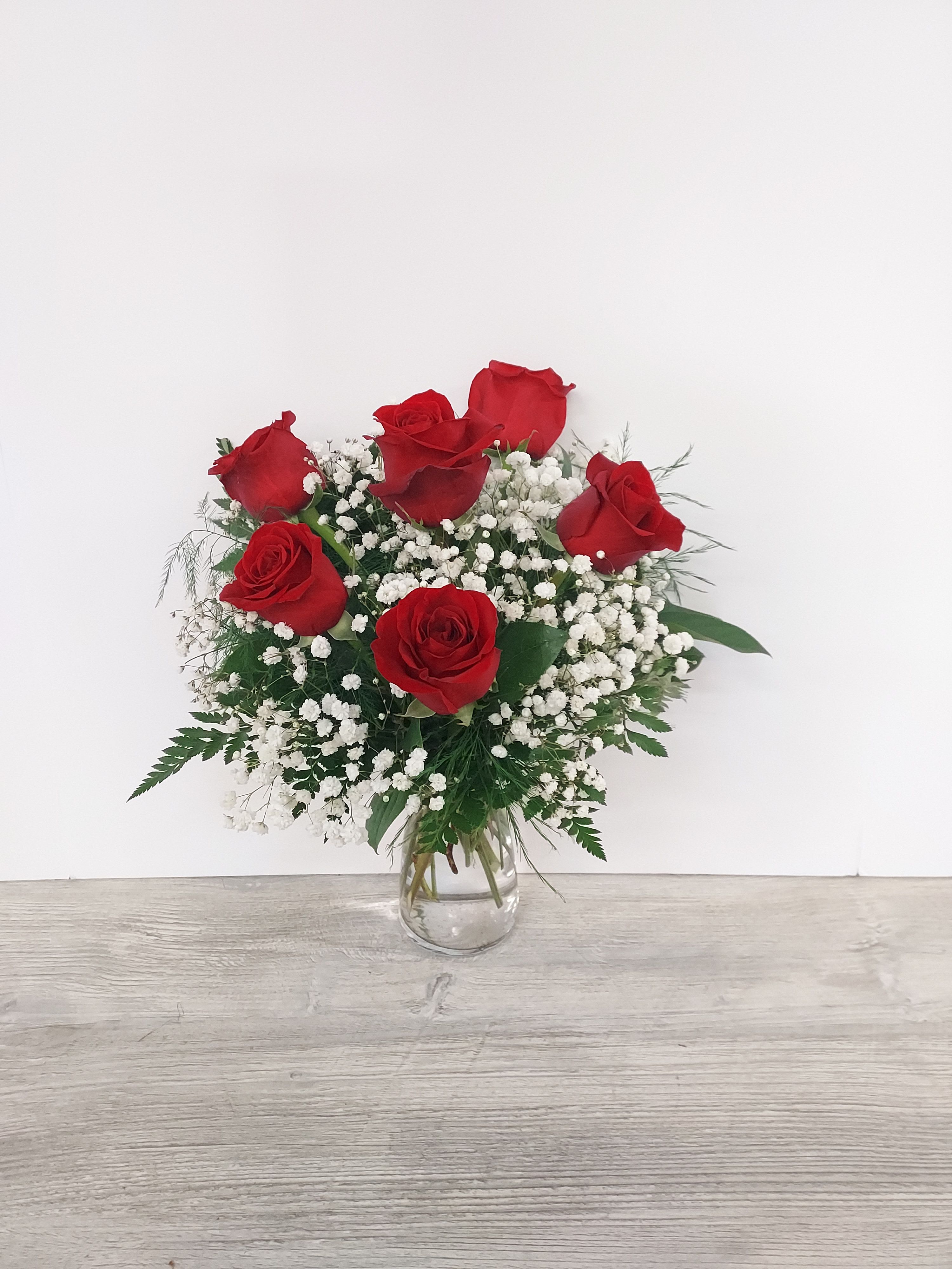 Arrangement of red roses and white baby's breath in a clear glass vase
