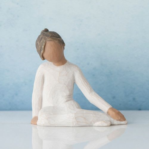 Small seated figurine in a white dress against a blue background
