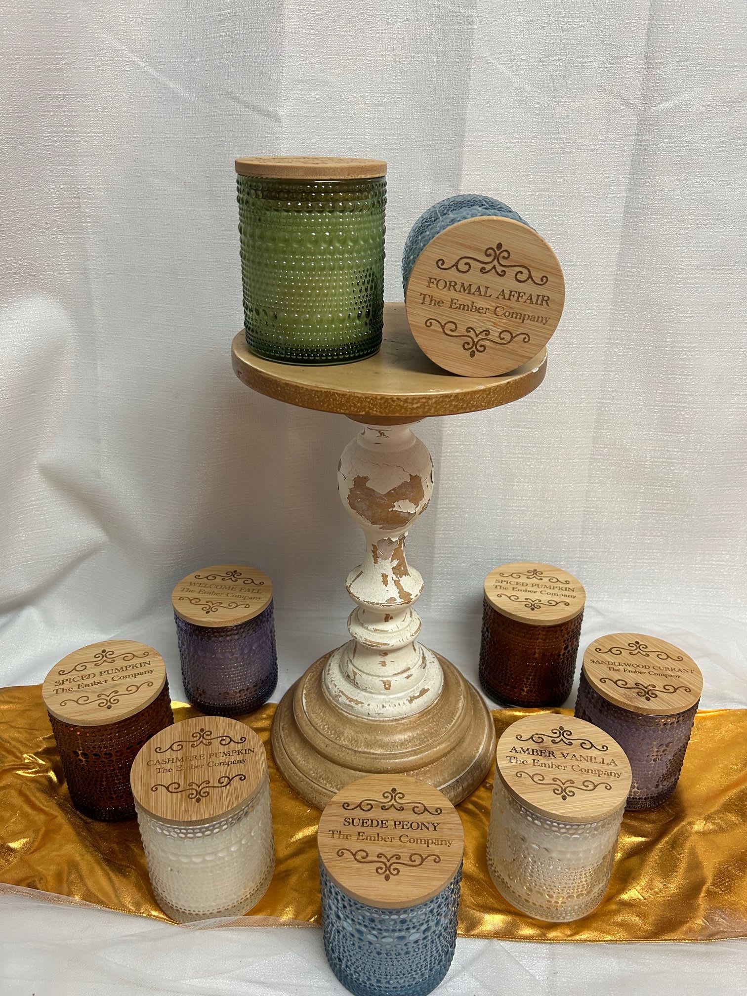 Assorted scented candles in textured glass jars on a pedestal stand